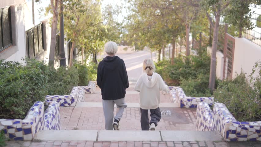 A boy and a girl are walking down the slopes in the park.