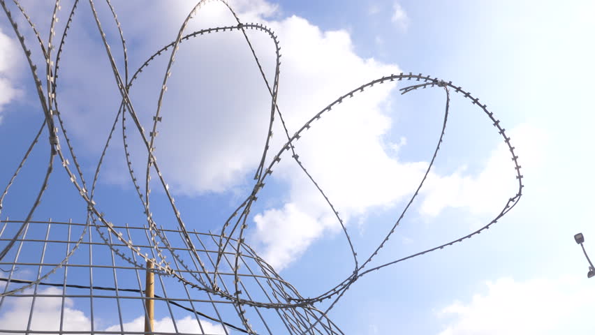 Border fence made of razor wire with sharp metal blades fence Royalty-Free Stock Footage #3412793619