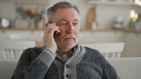 Positive senior man calls phone at home. Portrait old gray haired male talking on smartphone sitting on couch, smiling laughing enjoying conversation with friend, relative. Happy sociable person. - Powered by Shutterstock - Get 15% off with code: PIKWIZARD15