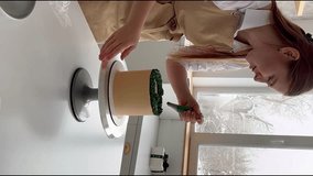 woman prepares cake and pastries. Decorates the cake with green cream. pastry cream. vertical video. High-quality shooting in 4K format.