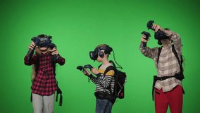 Teenage children use VR headset helmets to play an imitation game on a green background. Viewing 3d 360 virtual reality videos. Children in a virtual reality headset looking around. Chroma key. 