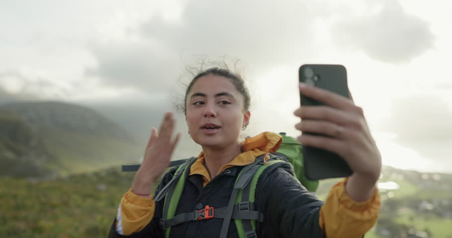 Woman, hiking and video call in nature, mountains and blow kiss with smile, hello and talking on adventure. Influencer girl, outdoor and happy on hill, fitness and wellness with emoji on social media