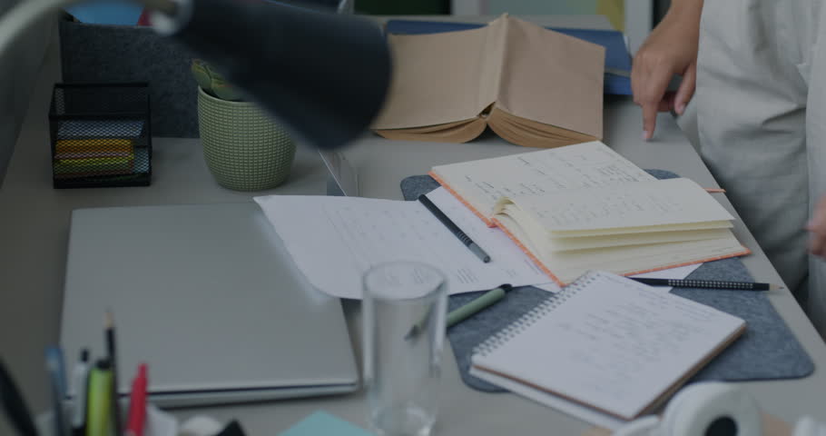Close-up of female hands tidying desk holding books and stationery objects cleaning apartment. Modern lifestyle and housework concept. Royalty-Free Stock Footage #3413007437