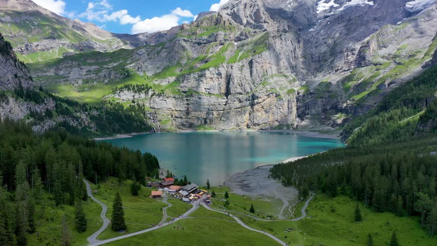 Famous Oeschinensee with Bluemlisalp mountain on a sunny summer day. Panorama of the azure lake Oeschinensee. Swiss alps, Kandersteg. Amazing tourquise Oeschinnensee with waterfalls, Switzerland. Royalty-Free Stock Footage #3413015887