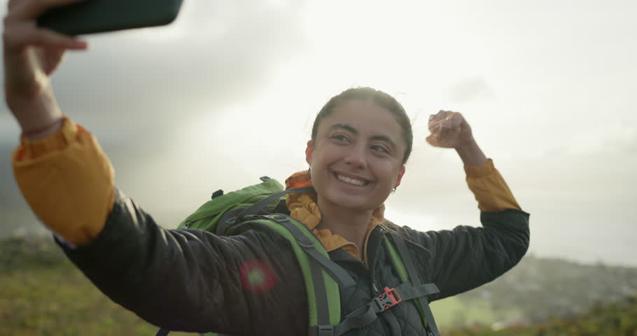 Woman, hiking and happy with video call, mountains and dancing with smile, cheers and talking on adventure. Influencer girl, outdoor and celebration on hill, fitness and achievement on social media