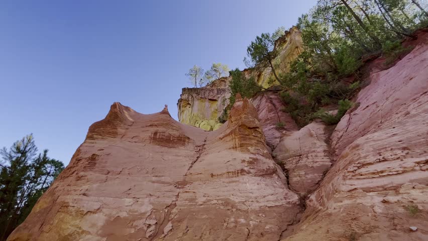 Ocher rocks with different layers of color in the evening light with some trees in France nature conservation Royalty-Free Stock Footage #3413059231
