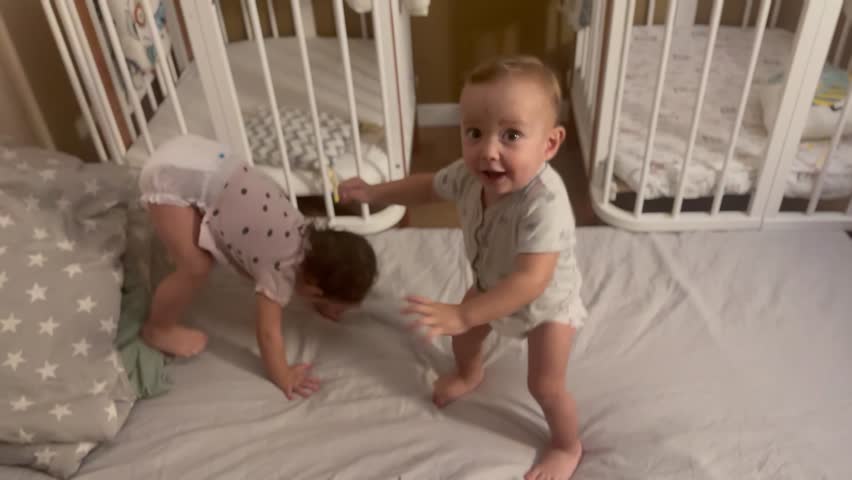 group of babies jumping on bed playing around. happy family kid dream concept. baby twins in the bedroom are freaking out jumping laughing. kids jumping and playing indoors lifestyle