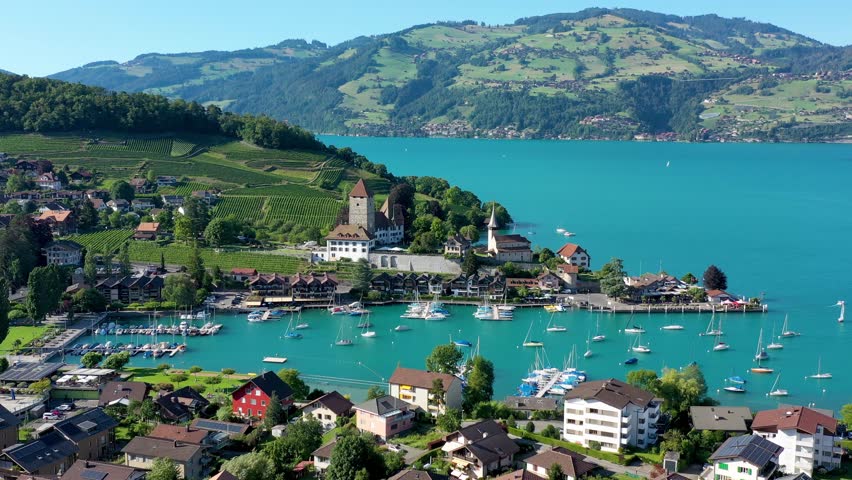 Aerial panoramic view of Spiez Church and Castle on the shore of Lake Thun in the Swiss canton of Bern at sunset, Spiez, Switzerland. Spiez Castle on lake Thun in the canton of Bern, Switzerland.