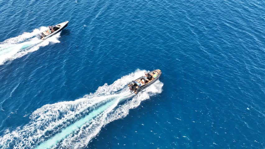 Aerial drone tracking video of inflatable rib speed boat cruising in high speed deep blue Aegean sea