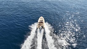 Aerial drone tracking video of inflatable rib speed boat cruising in high speed deep blue Aegean sea