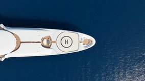 Aerial drone top down pan video of luxury yacht with wooden deck and helicopter landing pad anchored in deep blue Mediterranean sea