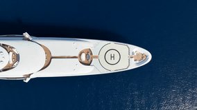 Aerial drone top down pan video of luxury yacht with wooden deck and helicopter landing pad anchored in deep blue Mediterranean sea - Powered by Shutterstock - Get 15% off with code: PIKWIZARD15