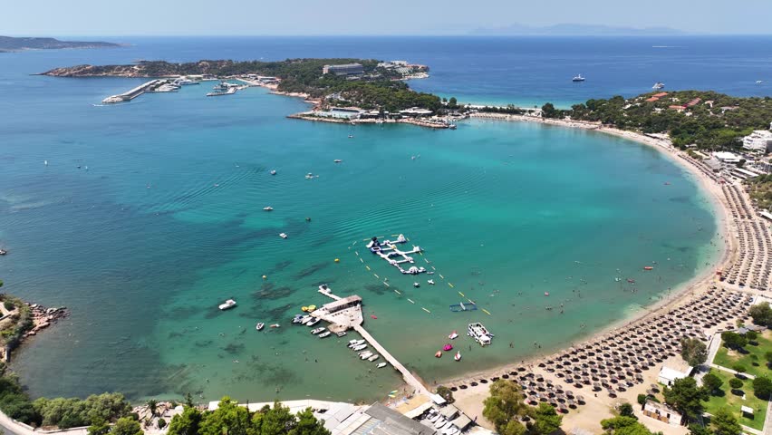 Aerial drone video of famous celebrity sandy beach Vouliagmeni in south Athens riviera with emerald crystal clear waters, Attica, Greece