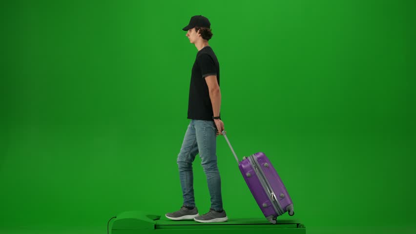 Portrait of traveler isolated on chroma key green screen background. Young man with suitcase in cap walking and looking around. Royalty-Free Stock Footage #3413123361