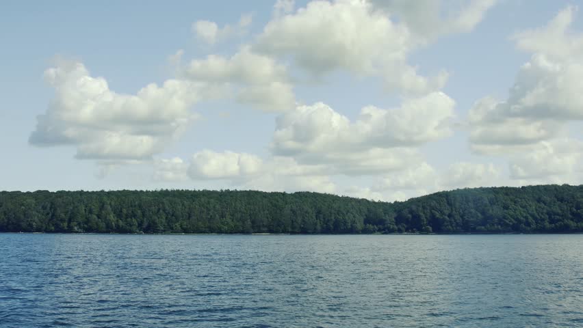 view from the sea to the shore with forest and clouds