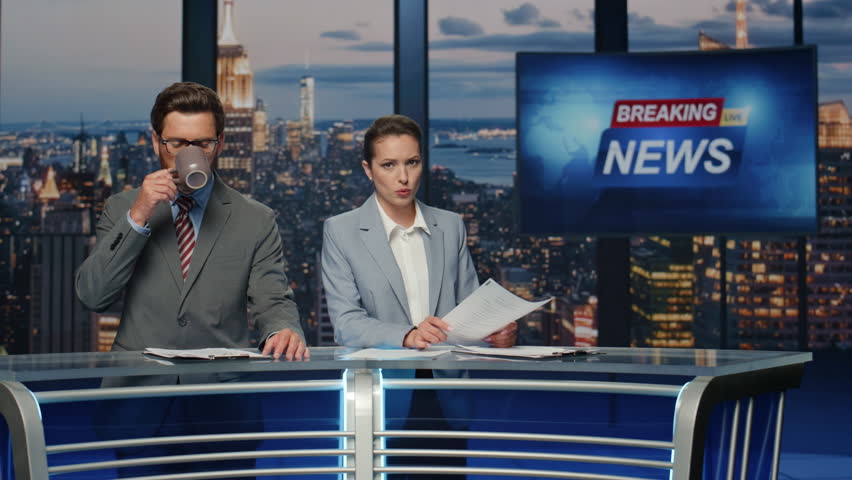 Elegant newscasters presenting daily breaking news in evening television show closeup. Serious professional presenters beginning broadcasting newscast. Confident hosts reporting about business event