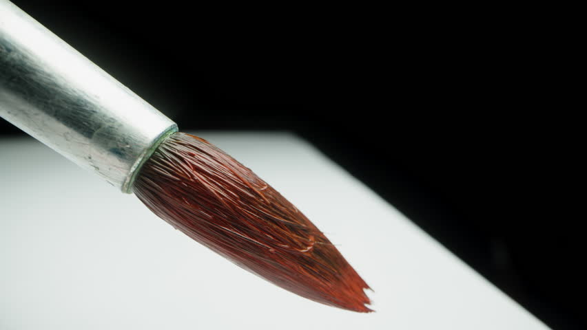 Brush with red paint, the artist draws a straight line, macro, the camera follows the brush.