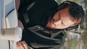 Headphones man writing notebook sitting summer park vertical oriented closeup. Inspired hispanic freelancer listening music working at nature. Pensive author writing new book at street cafe zone - Powered by Shutterstock - Get 15% off with code: PIKWIZARD15