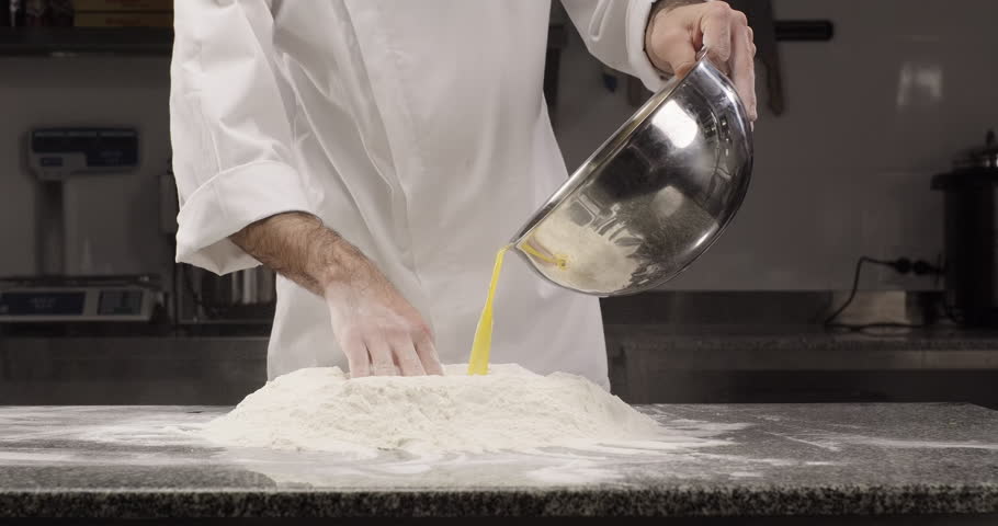Male hands pours whipped eggs into flour. Pastry chef prepares dough at bakery using traditional recipe