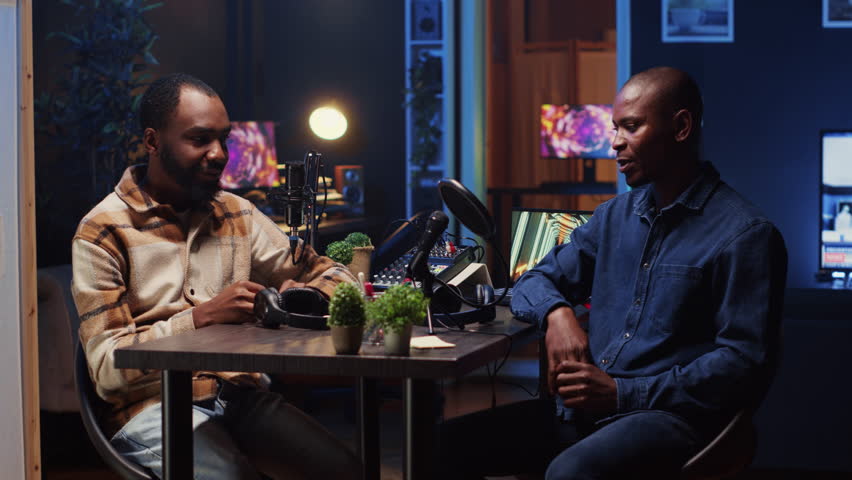 Podcast journalist fist bumping guest, ready to start listening to his interesting story while viewers watch from home. Host greeting african american man invited in studio to share facts