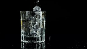 Ice cubes falling into a glass of water on a black background. Slow motion. Isolated on black background. - Powered by Shutterstock - Get 15% off with code: PIKWIZARD15