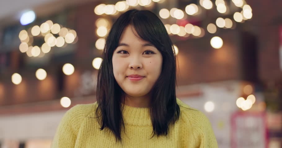 Japanese woman, face and happiness in city for travel, wellness and leisure on weekend vacation. Young person, smile and portrait in tokyo town on holiday, positive attitude and relax by bokeh lights