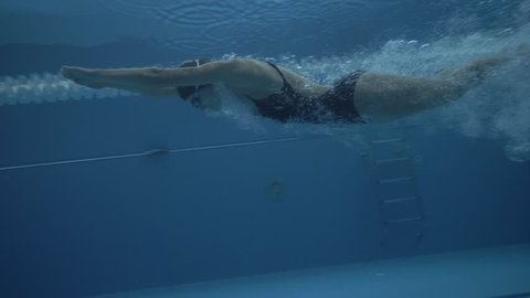 Woman swimmer jump on deep water in floating pool at start slow motion. Close up woman dive in transparentwater on swimming pool under water view 60 fps