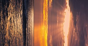 Tropical color cloudscape sunrise over calm sea waves and sun rays through the clouds vertical panorama 4k video