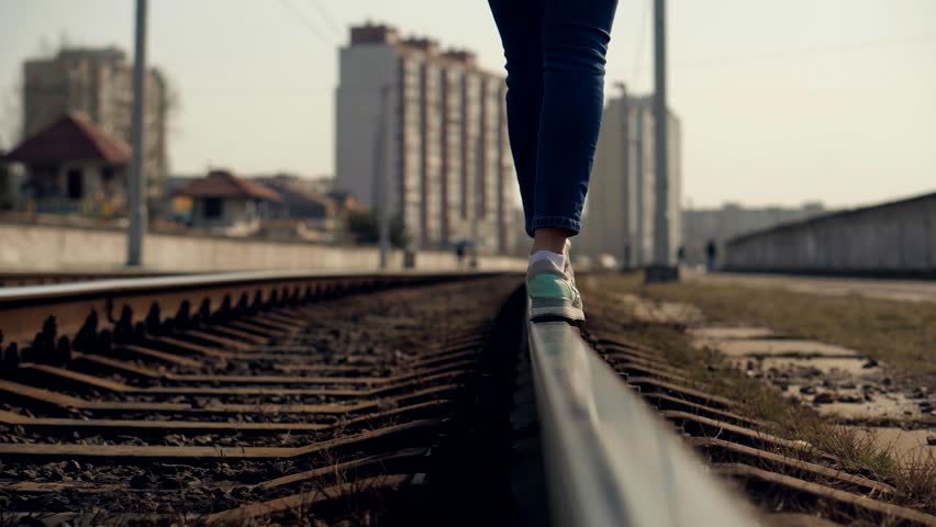 Girl Walks To Home On Railroad Tracks After Canceled Tram Public Transport .Tourist Legs Walking On Railway Middle Of Rail. Lonely Woman Feet In Jeans Walking On Rail Road When Train Or Tram Cancelled