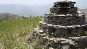 An ancient small pyramid shaped worship idol dedicated to Lord Shiva prayer place made of stones in the middle of a meadow with beautiful landscapes. Cultures of The Himalayas, Uttarakhand, India.