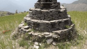 An ancient small pyramid shaped worship idol dedicated to Lord Shiva prayer place made of stones in the middle of a meadow with beautiful landscapes. Cultures of The Himalayas, Uttarakhand, India.