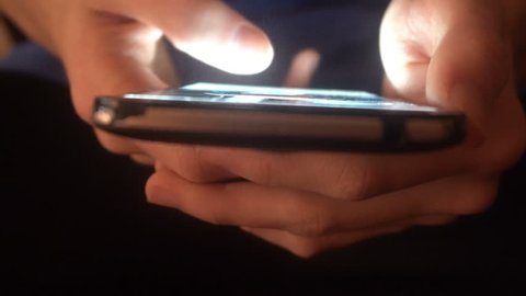 closeup of hands of a young man flipping through the news on the smartphone.