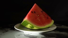 A large slice of ripe juicy watermelon rotates on a black background. Bright freshness of fruits. Summer delicacy. 4k footage.