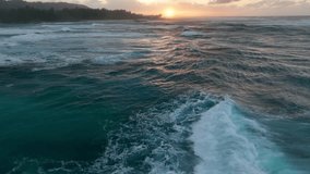 An aerial drone video captures the enchanting golden hour sunset in Hawaii, revealing a stunning view of big ocean waves breaking.