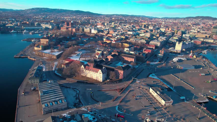 Oslo Aerial drone at waterfront Central train station, opera and Akershus Fortress along the seaside fjord, Norway during sunset