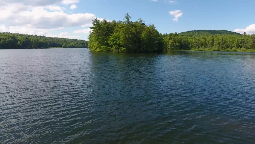 A spectacular 4K drone shot over Parker Pond and Pleasant Lake, located in Casco, Maine, USA. The camera moves low over the surface of the water, then rises and pans down over a forested peninsula.