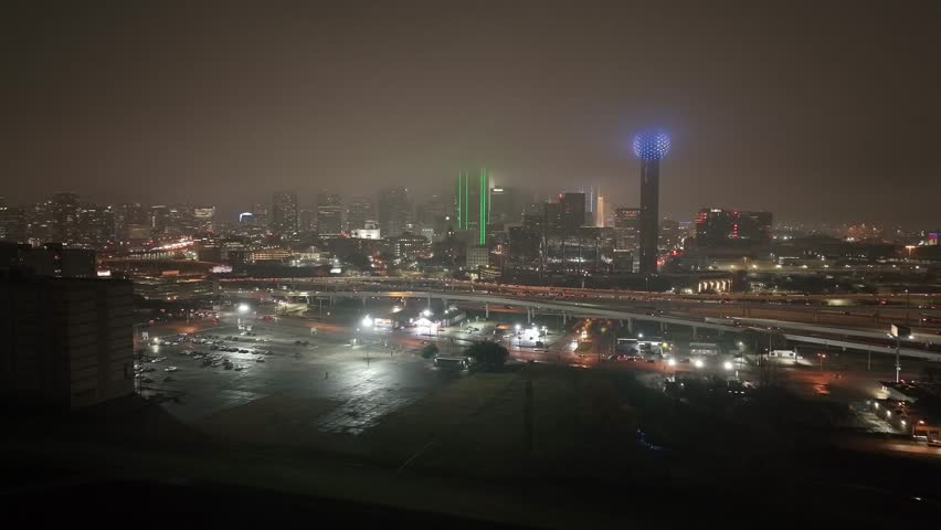 Dallas, Texas skyline at night with foggy weather and drone video circling.