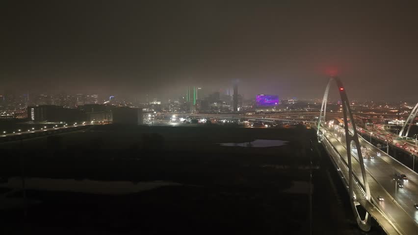 Dallas, Texas skyline at night with foggy weather and drone video moving up.