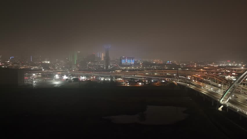 Dallas, Texas skyline at night with foggy weather and drone video stable wide shot.