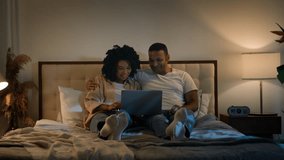 Carefree romantic date happy relaxed family African American married couple using laptop shopping man woman watching movie order delivery tickets with computer online at evening at home bed at night - Powered by Shutterstock - Get 15% off with code: PIKWIZARD15