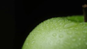 Wet green apple on a black background close-up