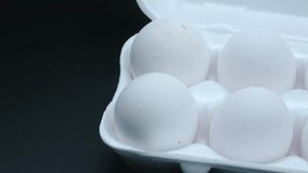 White chicken eggs in a tray general plan on a black background