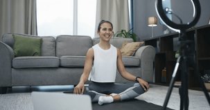 Fitness influencer, workout and woman with home live streaming, video recording and content creation. Young person on floor in living room with social media, filming on ring light and yoga or pilates