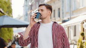 Happy brunette bearded adult man enjoying morning coffee hot drink and smiling. Relaxing, taking a break. Young guy walking on urban city center street, drinking coffee to go. Town lifestyles outside - Powered by Shutterstock - Get 15% off with code: PIKWIZARD15