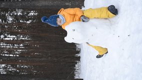 vertical video. a boy sits on an ice or snow figure of an animal and swings on it like on a toy in winter in a snowy forest - Powered by Shutterstock - Get 15% off with code: PIKWIZARD15