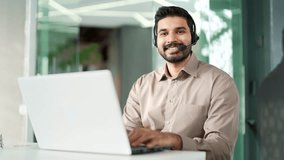 Portrait of a happy bearded corporate operator who works in customer support sitting at desk at workplace in business office. Confident call center agent or coach in wireless headset looking at camera - Powered by Shutterstock - Get 15% off with code: PIKWIZARD15