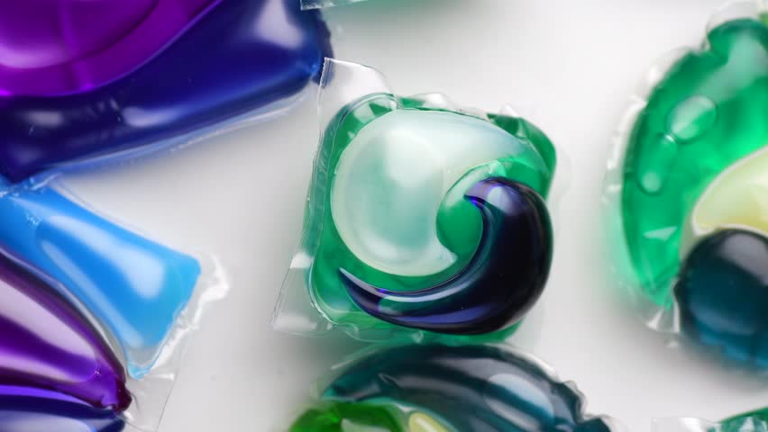 Washing capsules, colorful laundry pods. Colorful Soluble capsules with laundry gel detergent and dishwasher soap. Pile of washing pod capsules rotating. Detergent tablets. Top View, Flat Lay. 