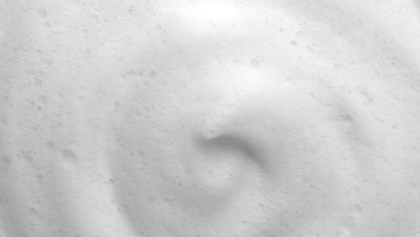 Foam background. Liquid soap bubbles, Froth bubbles backdrop. Soap foam popping bubble rotating, white backdrop. Soap sud macro structure close-up. Clean, cleaning, washing, laundry