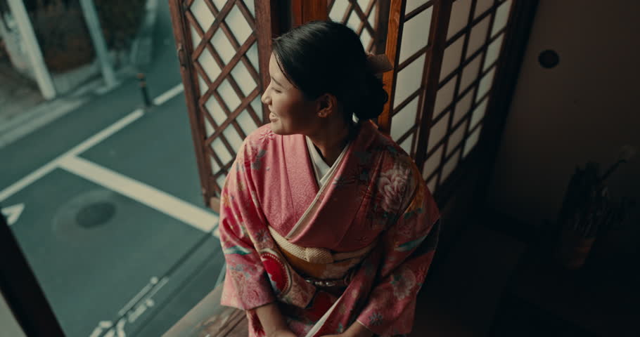 Thinking, relax and traditional japanese woman with smile for reflection, calm and wellness in morning. Kimono, culture and person in home with view for thoughtful, wondering and happy in living room Royalty-Free Stock Footage #3414110705