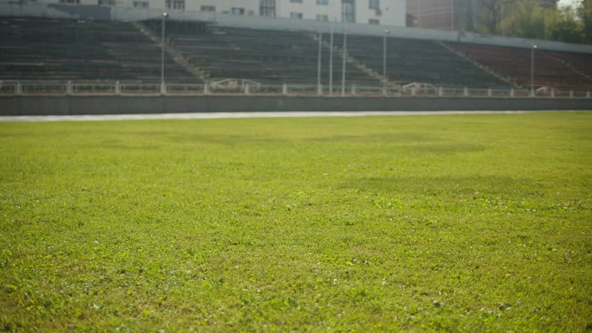 Young woman doing morning exercises in the sport stadium wearing green neon shorts. Sporty girl lay out a sports mat on the green grass. Outdoor. Nature